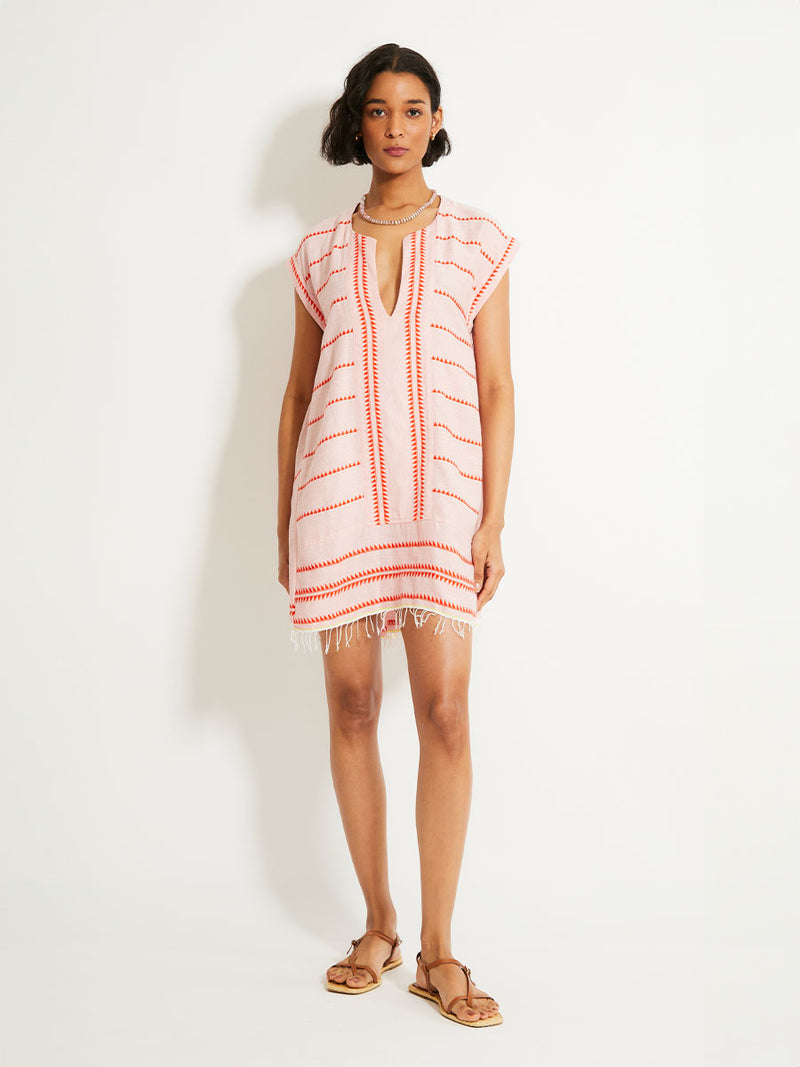 Woman Standing Wearing lemlem ELINA Caftan featuring vibrant orange red Tibeb pattern on a soft antique rose pink background, with a hint of citron tipping.