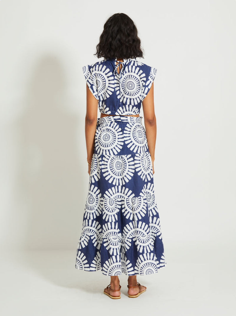 Back of a Woman Standing Wearing lemlem SANAA | Skirt Featuring a bold geometric medallion pattern on navy background, inspired by traditional Tibeb motifs.